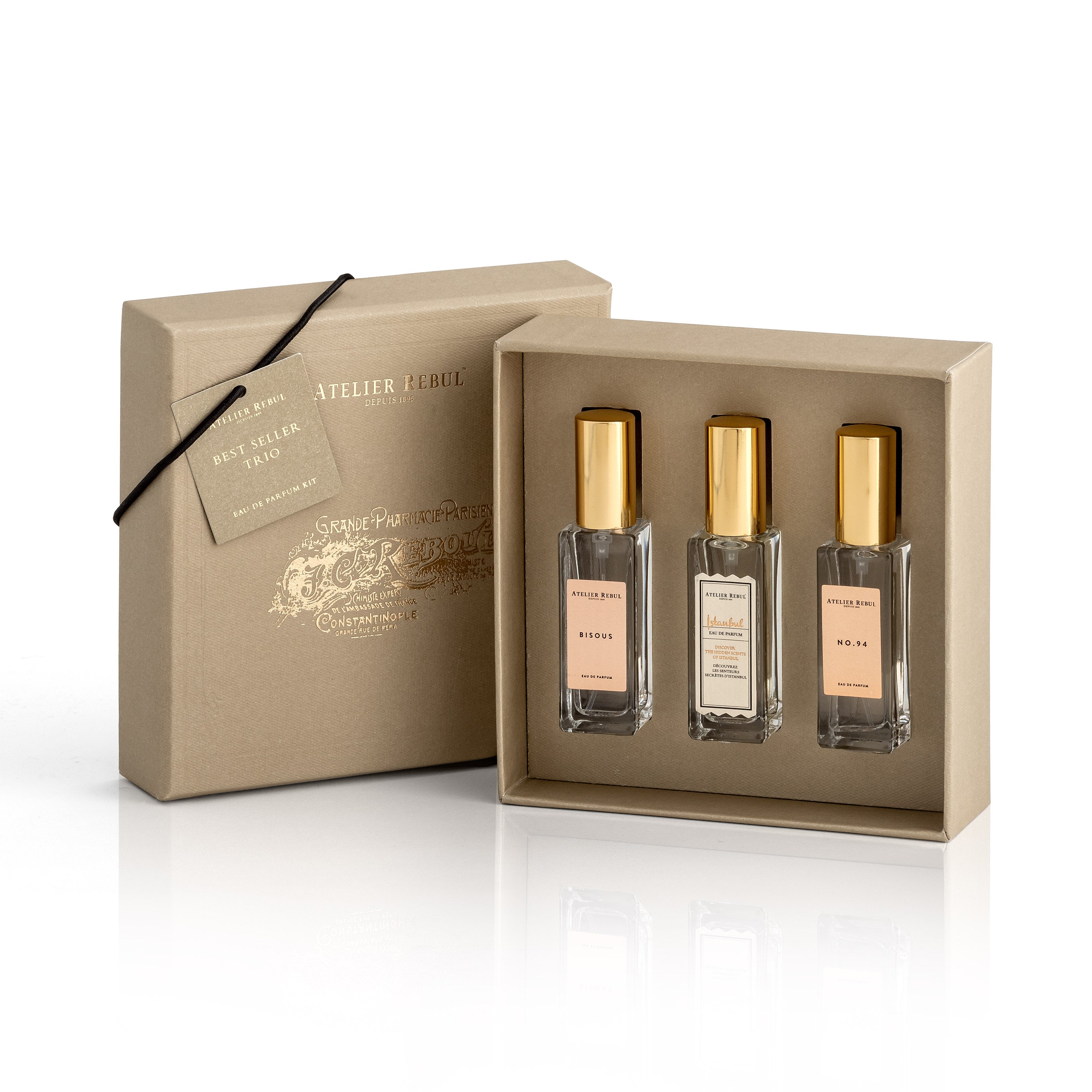 drei parfumflaschen in geoeffneter und aufgestellter geschenkbox. beige und gold.