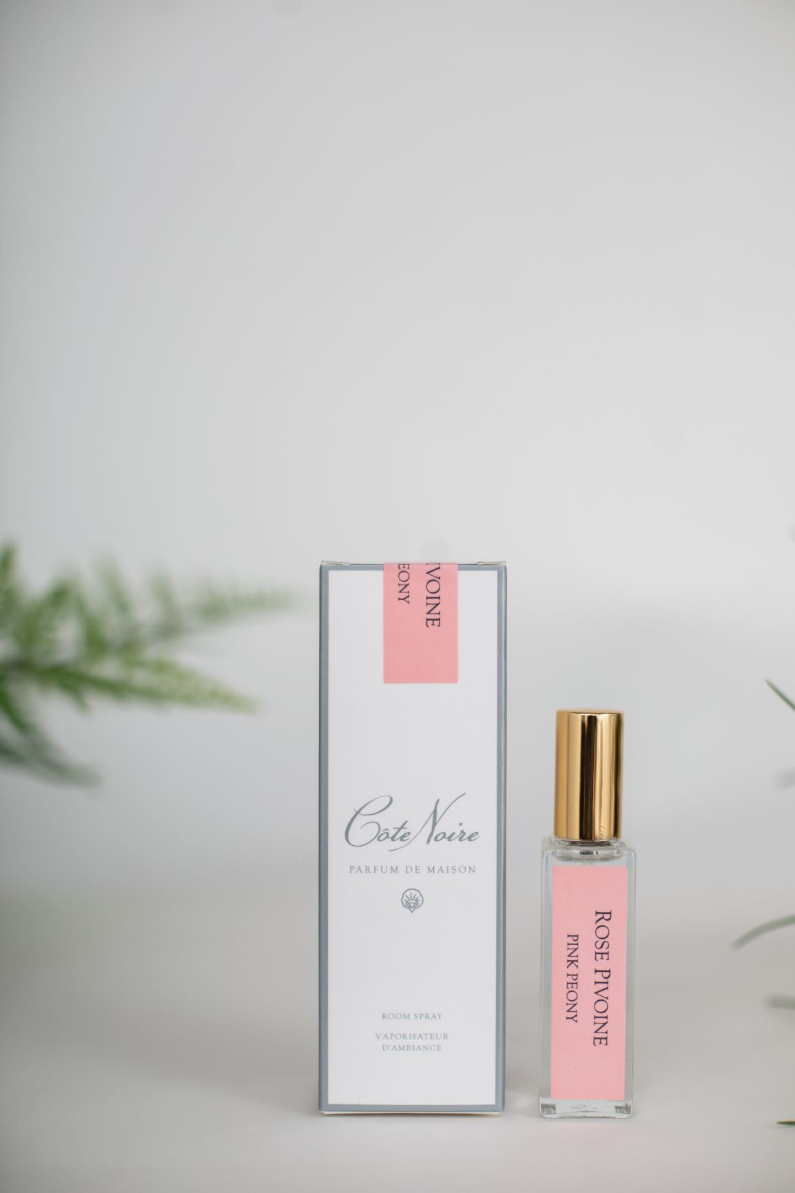 parfumflaeschchen mit goldenem deckel neben weisser verpackung. weisser hintergrund. pink peony.