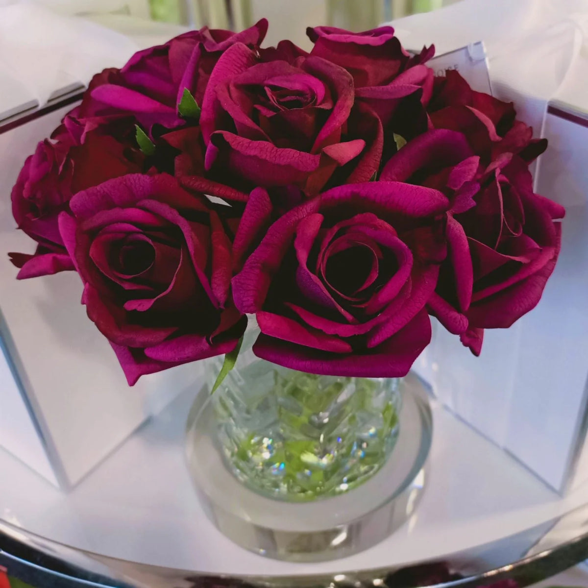 nahaufnahme der dunkelroten rosenknospen im gemusterten glas.