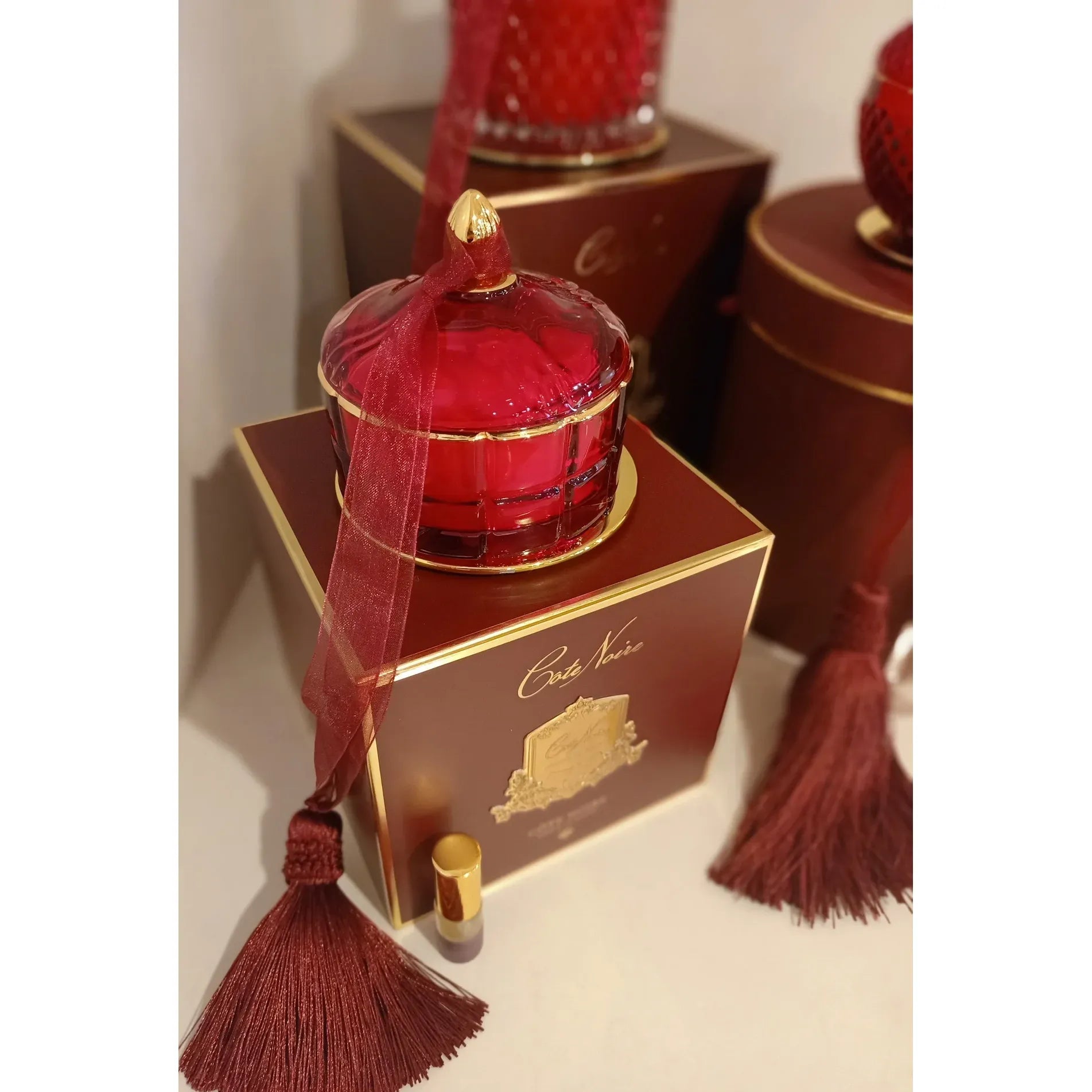 Elegante Detailaufnahme der Côte Noire Art Duftkerze in tiefem Rot mit goldenen Akzenten.