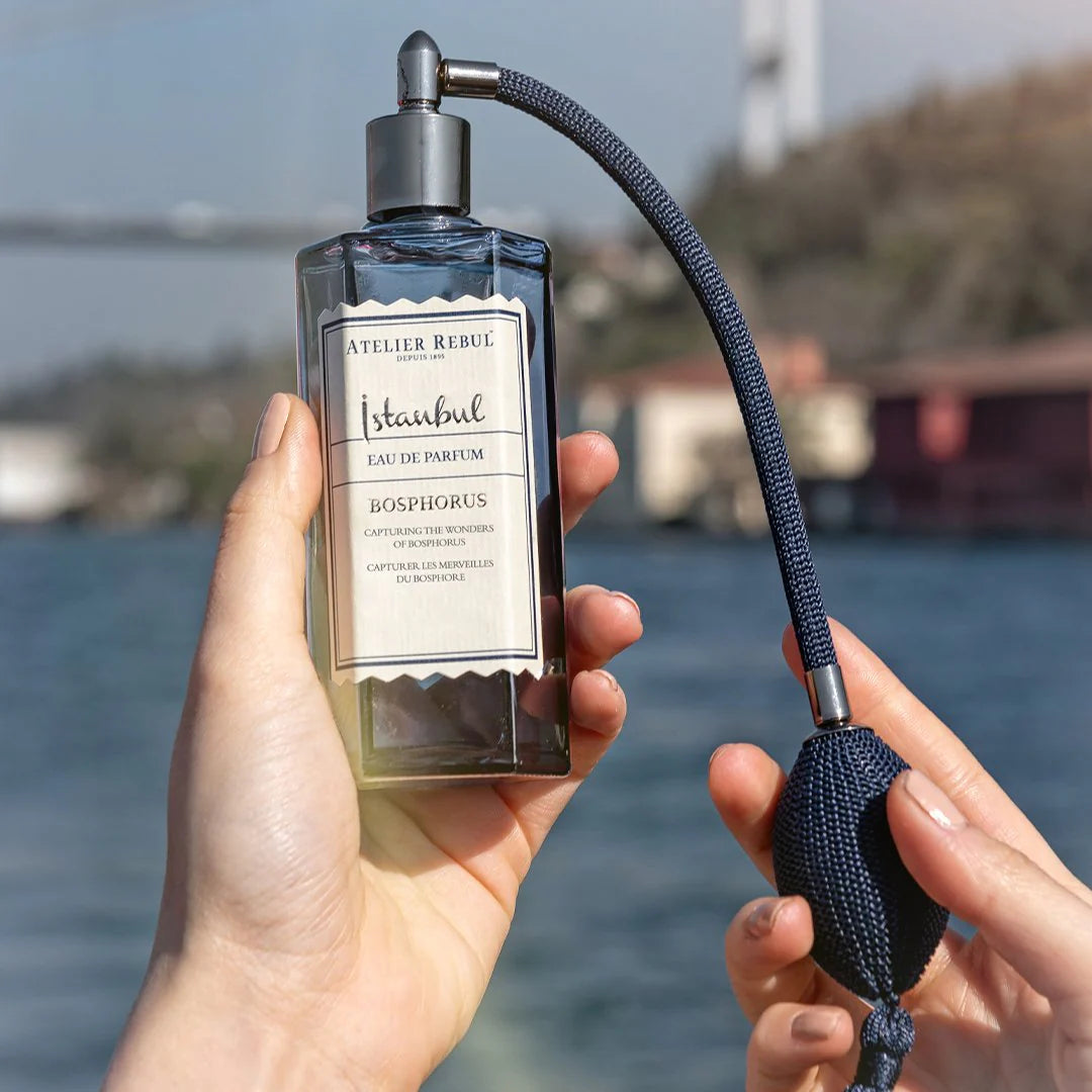 eau de pafrum istanbul le bosphorus in hand gehalten mit blick auf das meer im hintergrund.