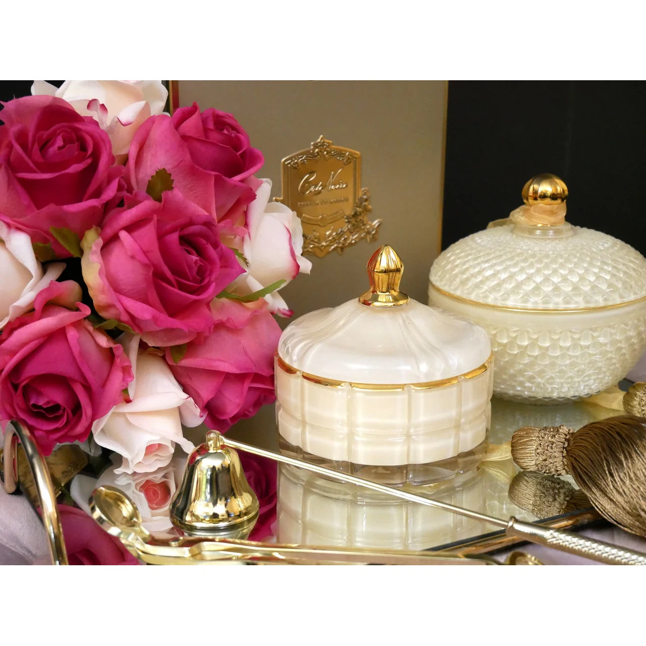 Luxuriöse Duftkerze Blonde Vanilla mit goldenem Zubehör, Rosen und schwarzer Vase auf Tablett