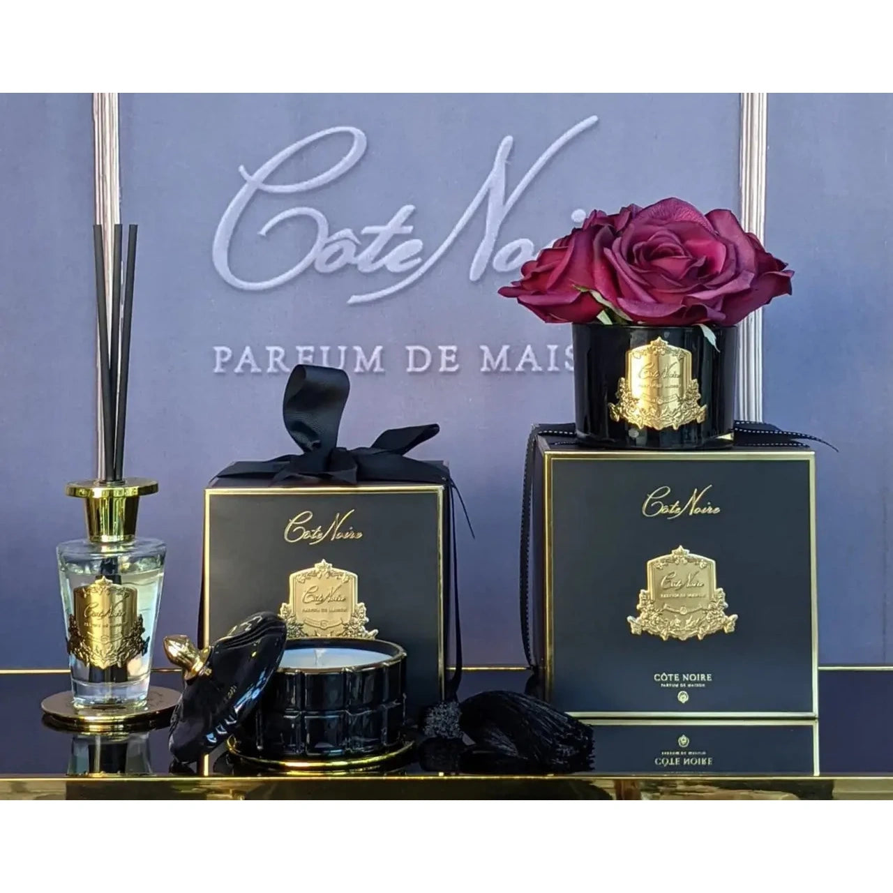 Duftkerze French Morning Tea mit Diffusor, schwarzen Geschenkboxen und violetten Rosen auf goldfarbenem Tablett