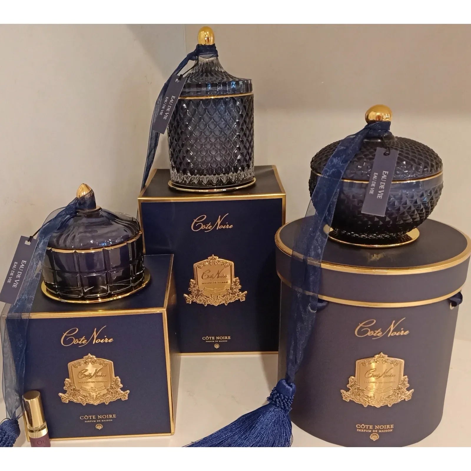 Côte Noire Duftkerzen Set Eau De Vie im Regal – navyfarbenes Glas mit goldenen Details