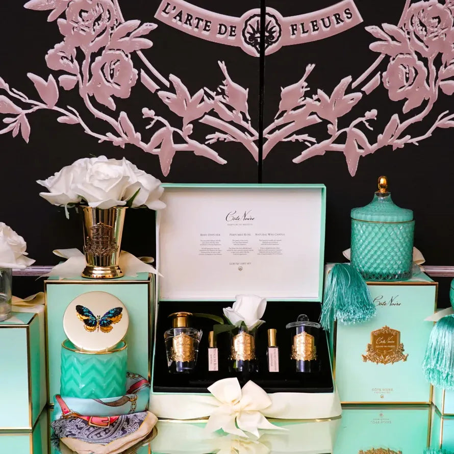 Luxuriöses Duftset Cote Noire Persian Lime mit Geschenkbox, weißen Rosen und Kerzen im stilvollen Ambiente