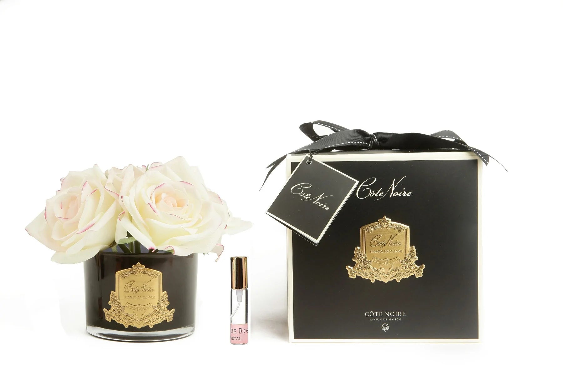 5 weisse rosen mit pinkem rand in dunklem glas mit goldenem emblem. dazu duftspray und schwarze verpackung.