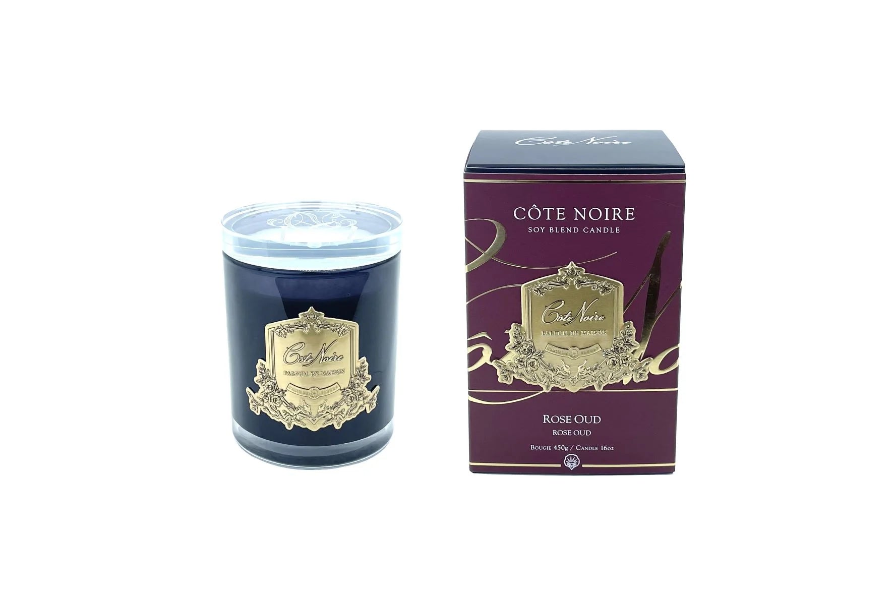 rose oud duftkerze in dunklem glas mit glasdeckel neben dunkelroter verpackung vor weissem hintergrund.