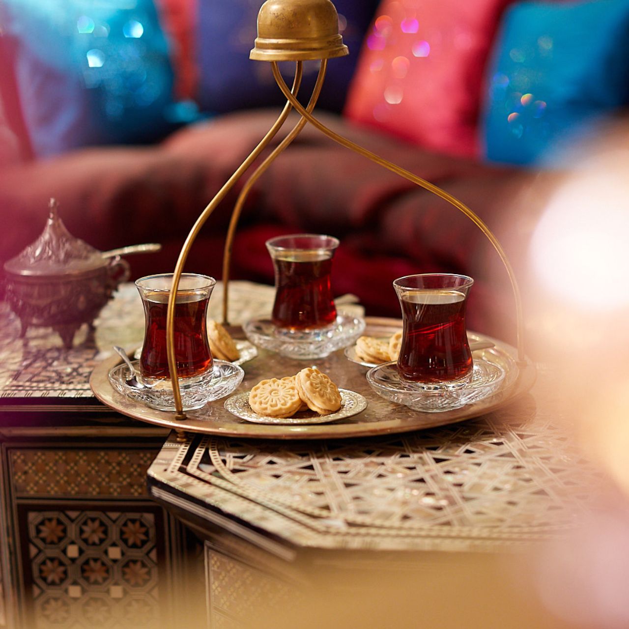Traditionelles orientalisches Teeservice mit drei Gläsern schwarzem Tee und kunstvoll verzierten Keksen auf einem dekorativen Tablett