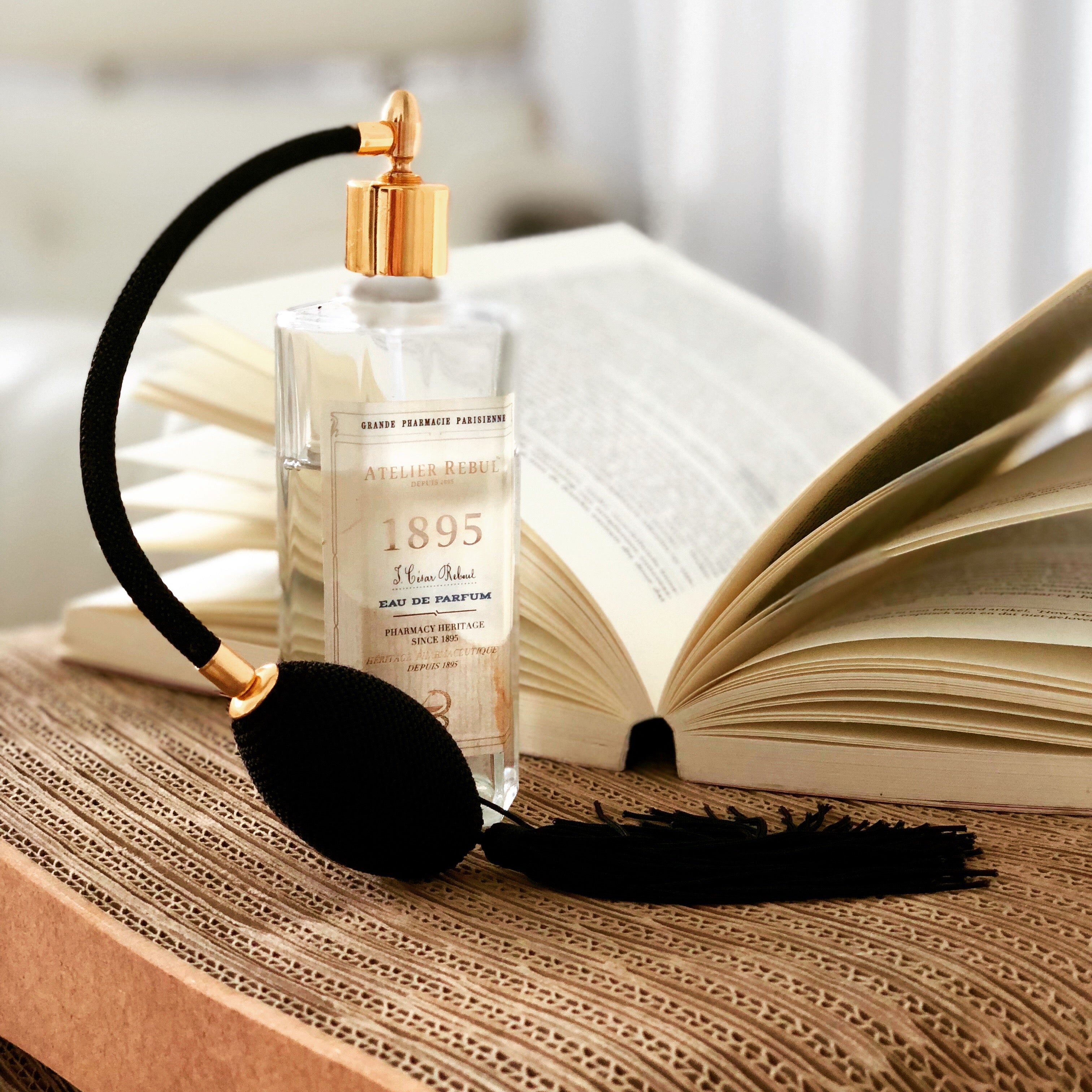1895 parfum 125ml glasflasche mit pumpspray auf tisch neben offenem buch