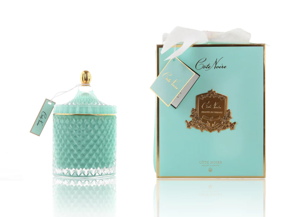 cote noire grand art duftkerze in dekorativem glas, daneben verpackung mit geschenkschleife, tuerkis und gold.