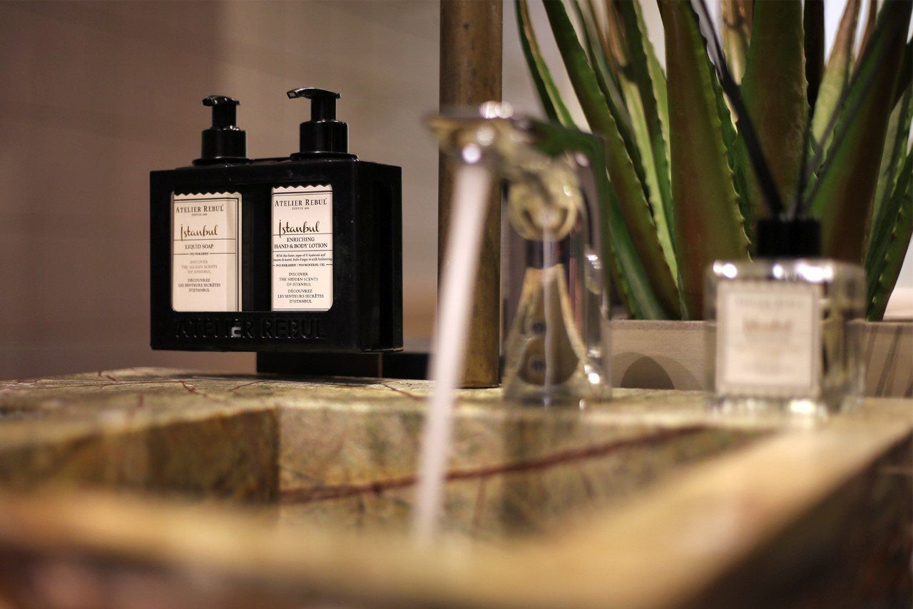 istanbul hand und bodylotion in schwarzer pumpflasche mit fluessigseife auf marmor waschbecken mit laufendem wasser