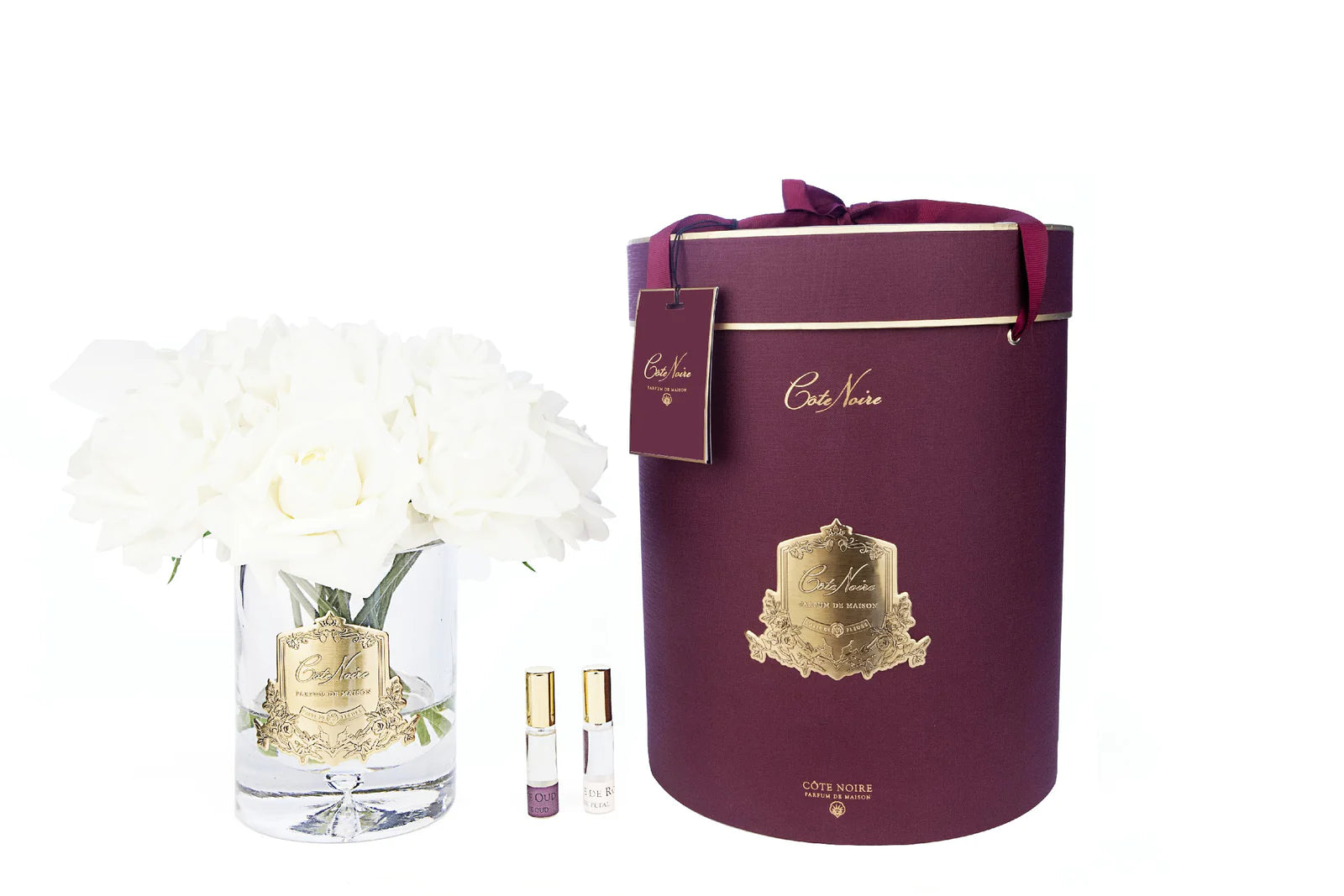 13 cremeweisse rosen arrangiert in einer edlen glasvase, zwei parfumsprays und eine luxurioese runde geschenkbox in burgunder.