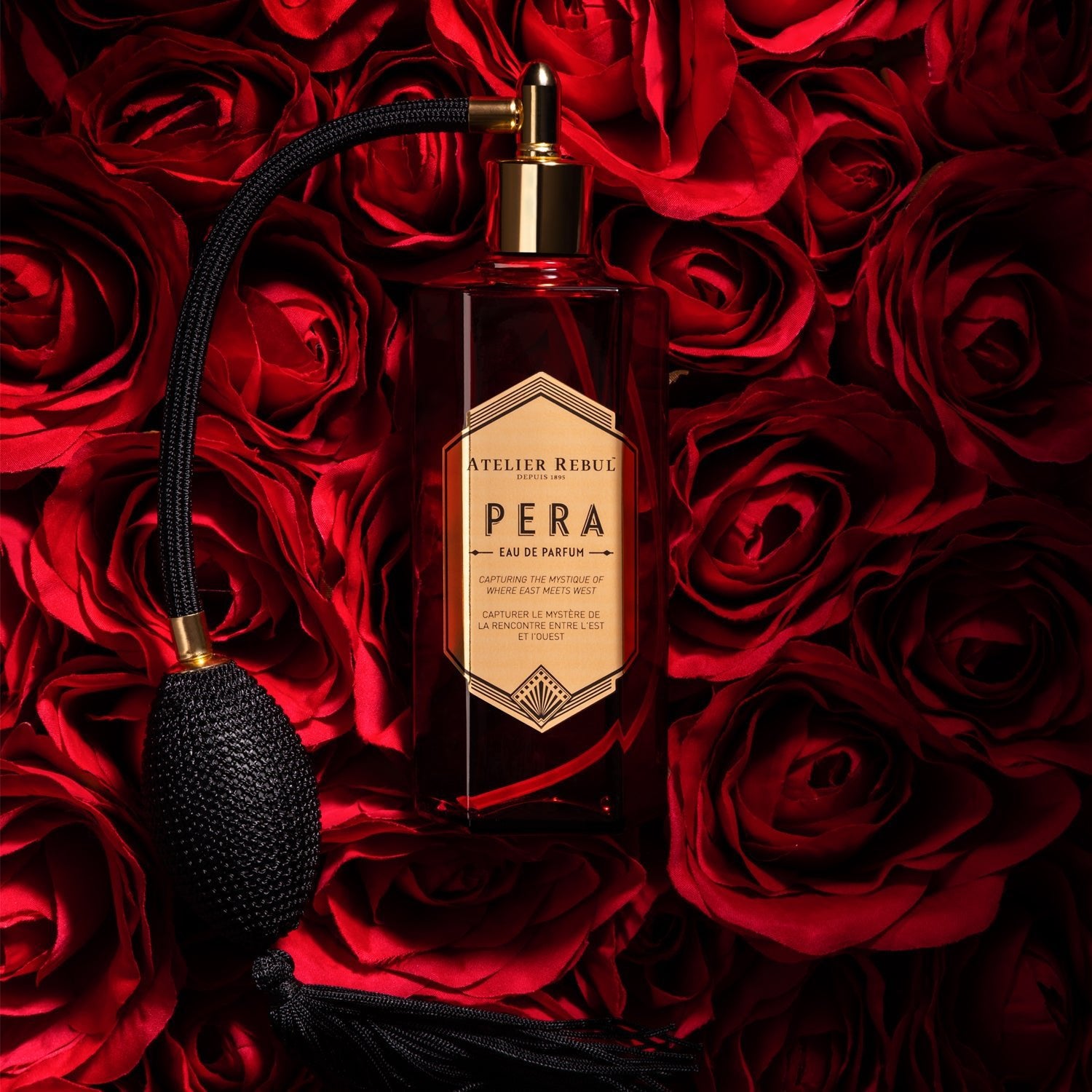 auf einem meer von roten rosen liegt die rote glaspumpsprayflasche von atelier rebul pera edel und stylisch