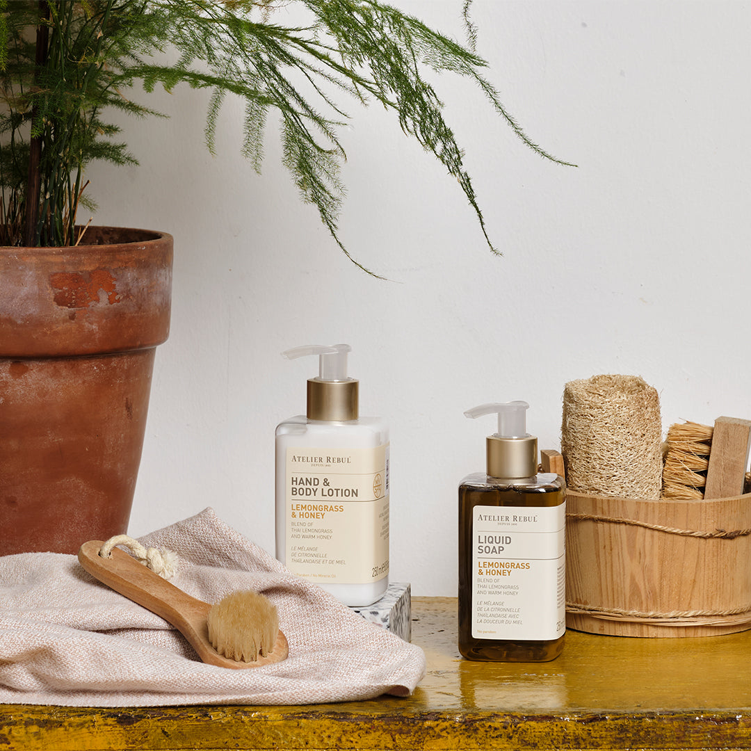 set aus lotion und fluessigseife auf ablageflaeche neben topf mit pflanze. honigfarben.