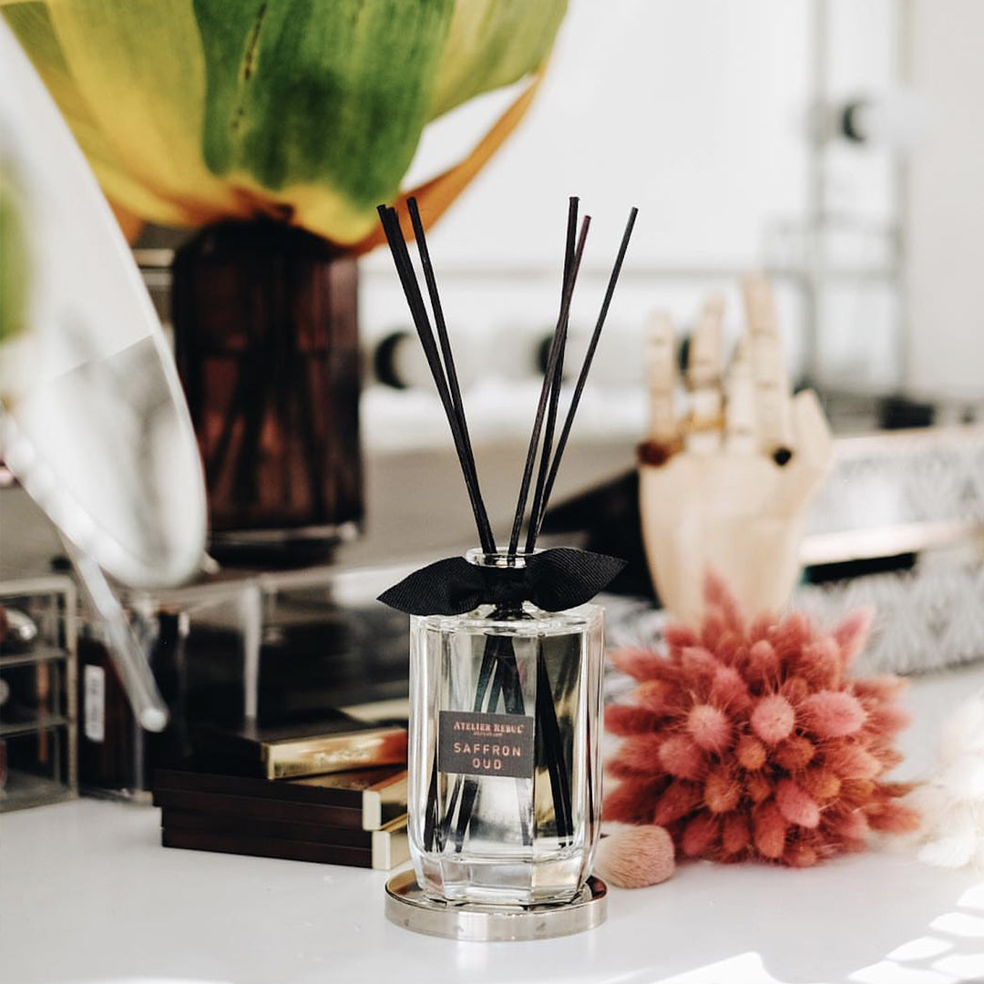 vor dem verschwommener dekorationshintergrund steht die rechteckige glasflasche duftstaebchenflasche