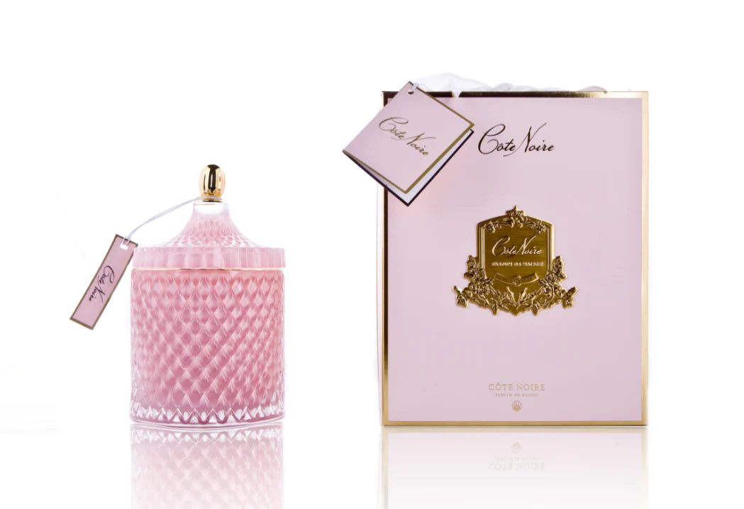 cote noire grand art duftkerze in dekorativem, daneben verpackung mit geschenkschleife, pink und gold.