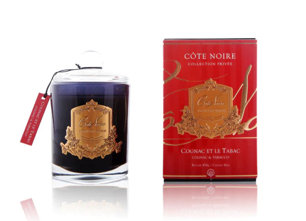 cote noire duftkerze in dunklem glas neben roter verpackung. weisser hintergrund