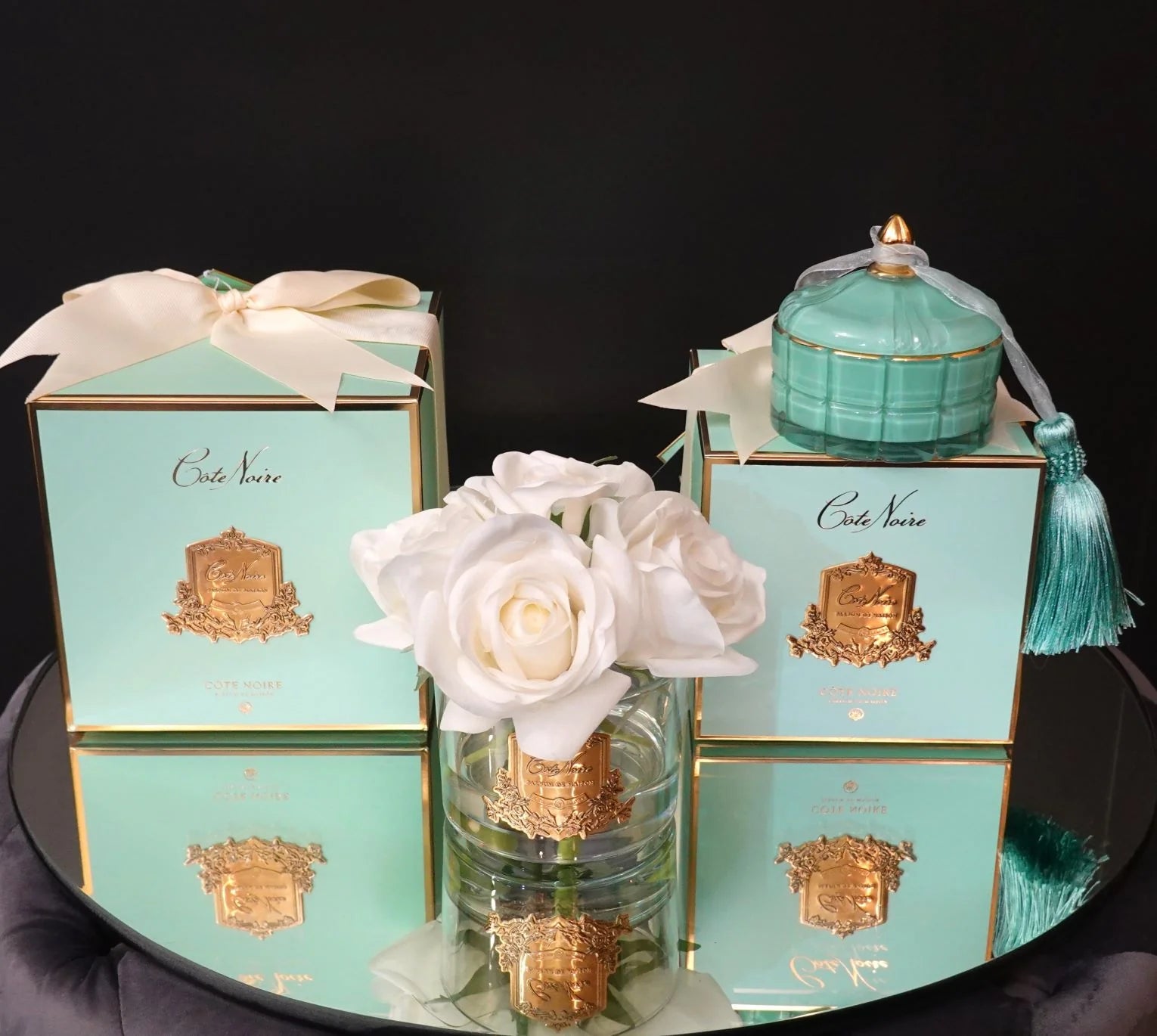 duftblume ivory white umgeben von zwei jadegruenen geschenkboxen, sowie der farblich passenden art duftkerze persian lime.