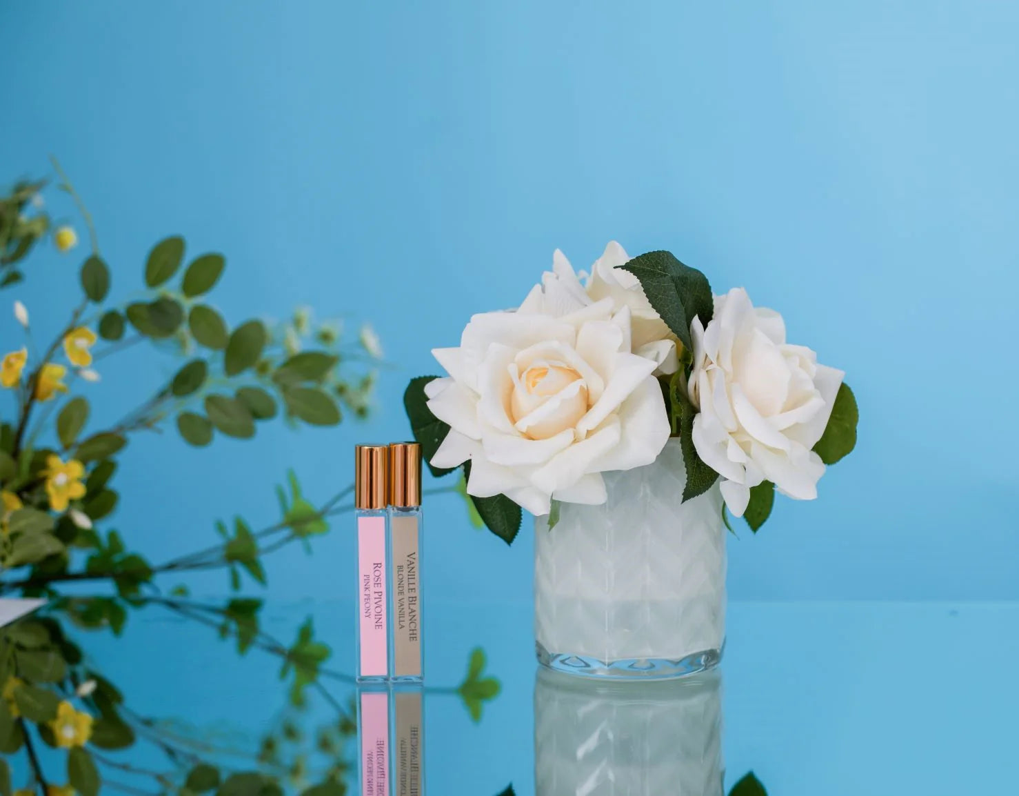 herringbone duftblume und zwei duftsprays auf blau spiegelndem tisch. blauer hintergrund 