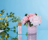 rosa herringbone duftblume mit zwei duftsprays auf blau spiegelndem tisch. blauer hintergrund.