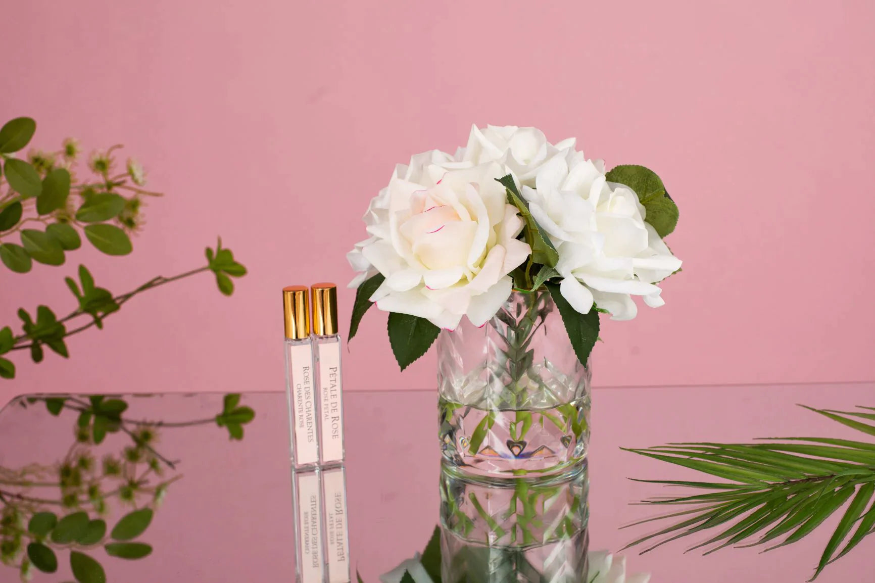 duftblumen im herringbone auf glastisch, der den rosa hintergrund spiegelt.