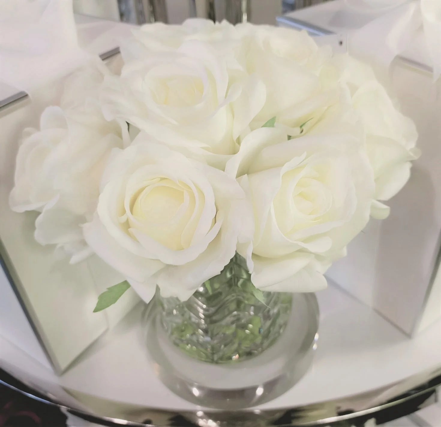frontsicht auf weisse rosen in gemustertem glas auf einer runden glasscheibe.