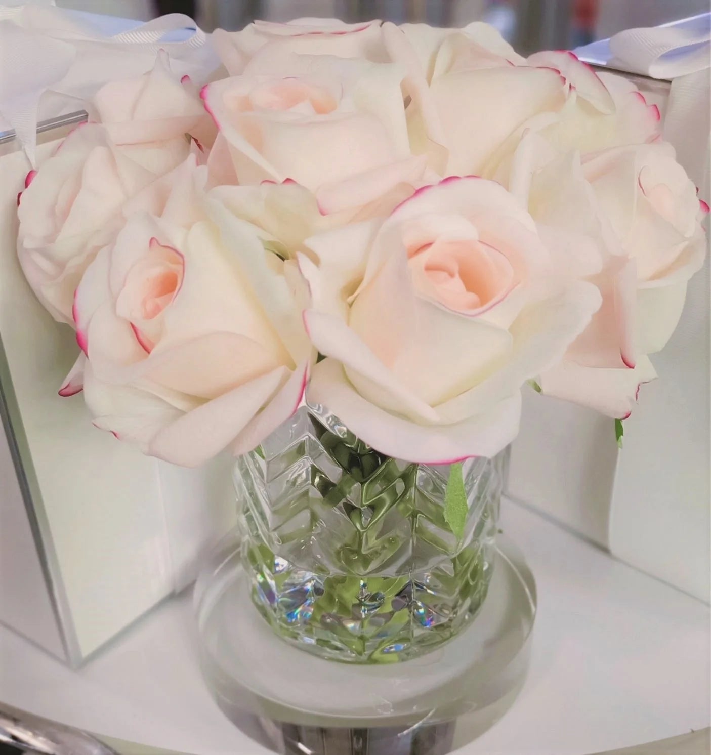 frontsicht auf pink blush rosen in gemustertem glas auf einer runden glasscheibe.