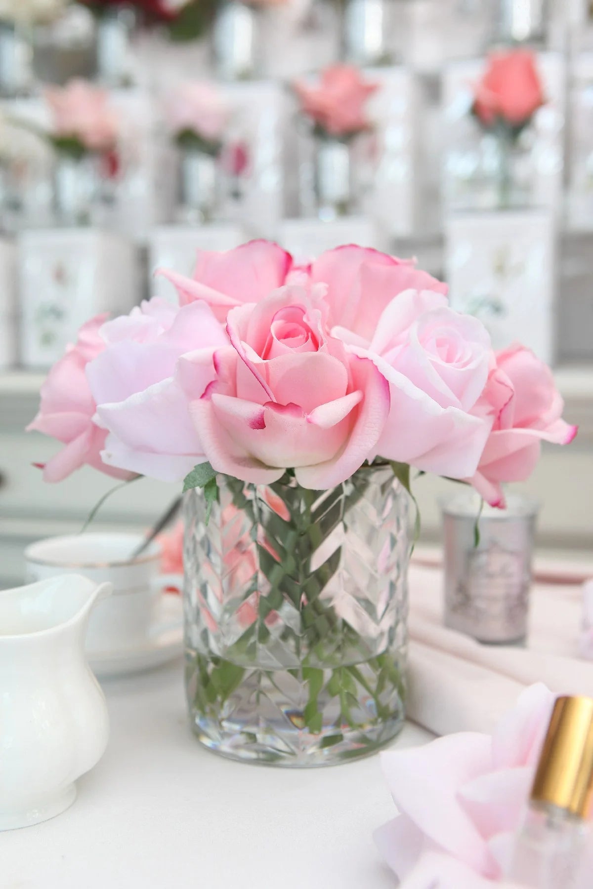 frontsicht auf mixed rosa rosen auf weiss gedecktem tisch.