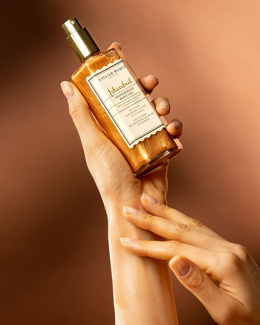 istanbul shimmering oil in einer weiblichen hand auf orange-braunem hintergrund.