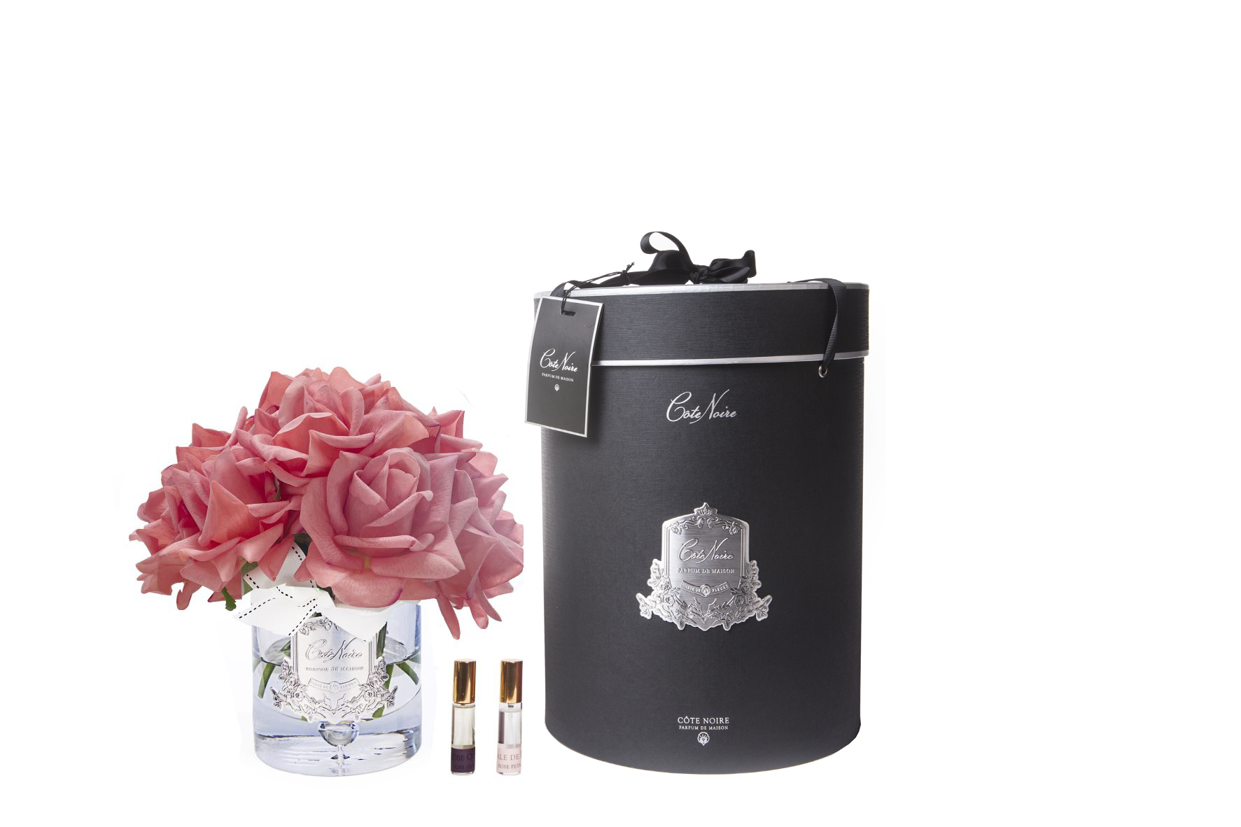 13 pfirsichfarbene rosen arrangiert in einer edlen glasvase, zwei parfumsprays und eine luxurioese runde geschenkbox in schwarz.