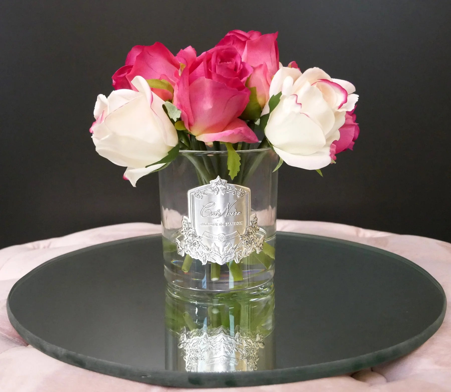 pink und weiss gemischter rosenstrauss in hellem glas mit silberner inschrift auf spiegelnder scheibe.