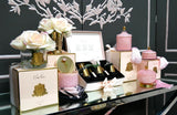 set aus verschiedenen rosa dulftblumen und duftkerzen von cote noire auf spiegelndem tisch.