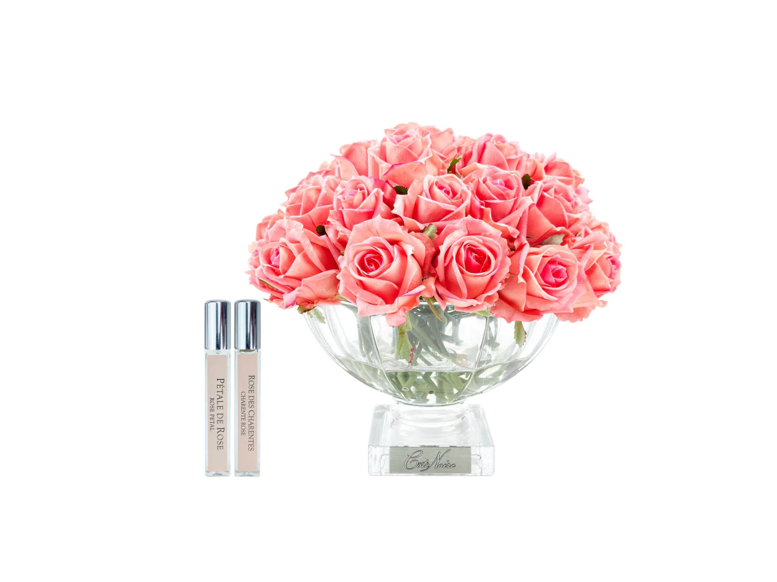 pfirsichweisse rosen in nobler glasvase neben zwei parfumsprays. weisser hintergrund