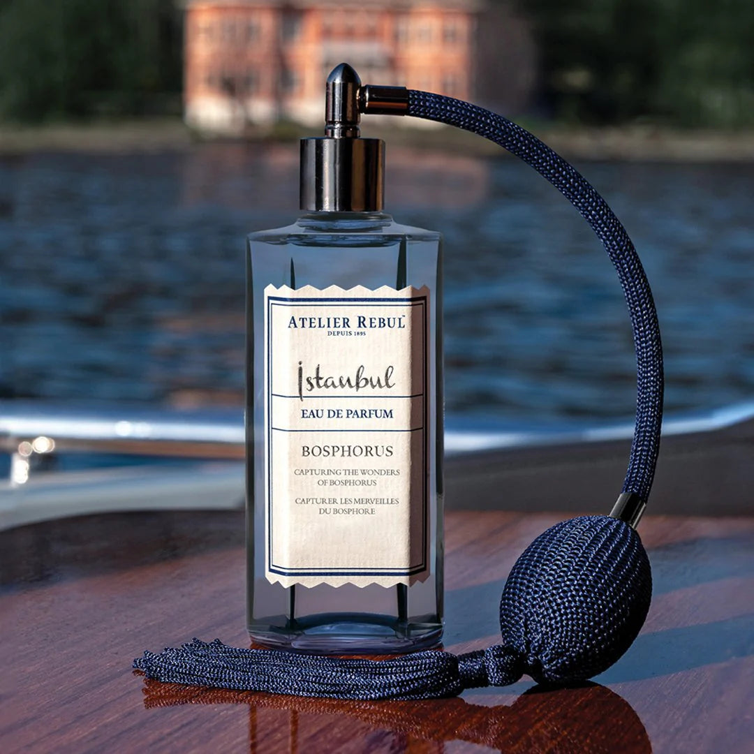 istanbul bosphorus eau de parfum auf glaenzendem holztisch. haus am bosporus meer im hintergrund.