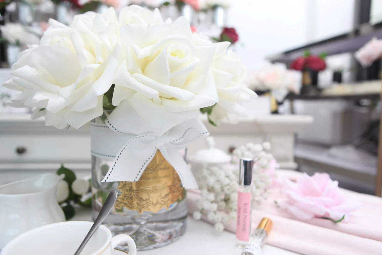Côte Noire Duftblume in Elfenbeinweiß – arrangiert auf einem Schminktisch mit Parfum und zarten Details für feminine Eleganz.