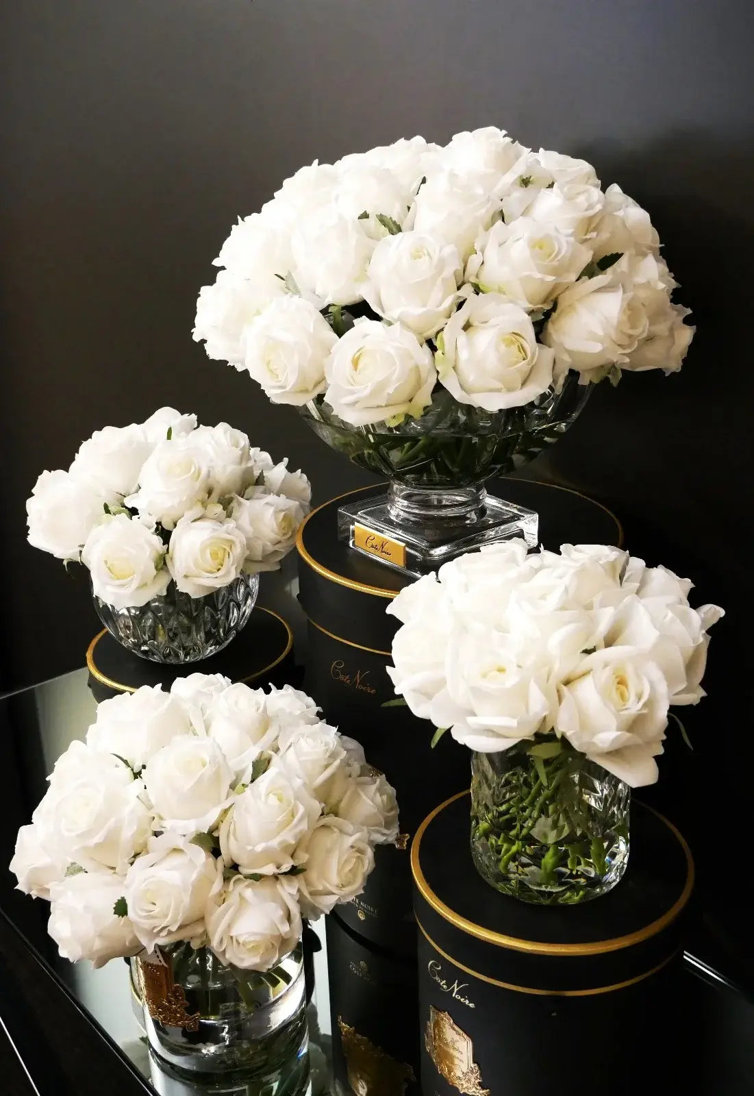 Verschiedene Duftrosen-Arrangements in Weiß – dekorative künstliche Blumen mit Glasvasen und schwarzer Box