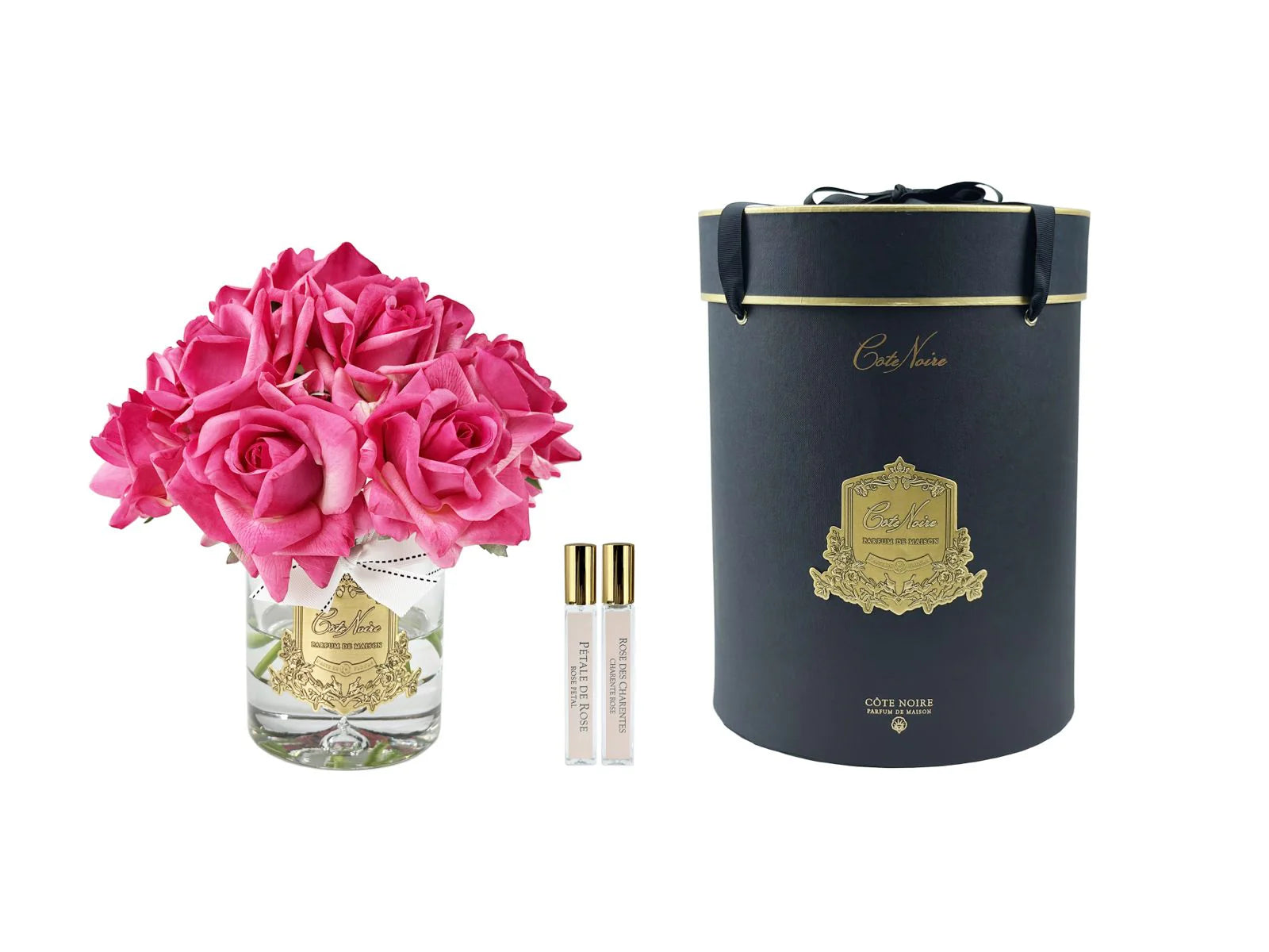 13  magentafartbene rosen arrangiert in einer edlen glasvase, zwei parfumsprays und eine luxurioese runde geschenkbox in schwarz.