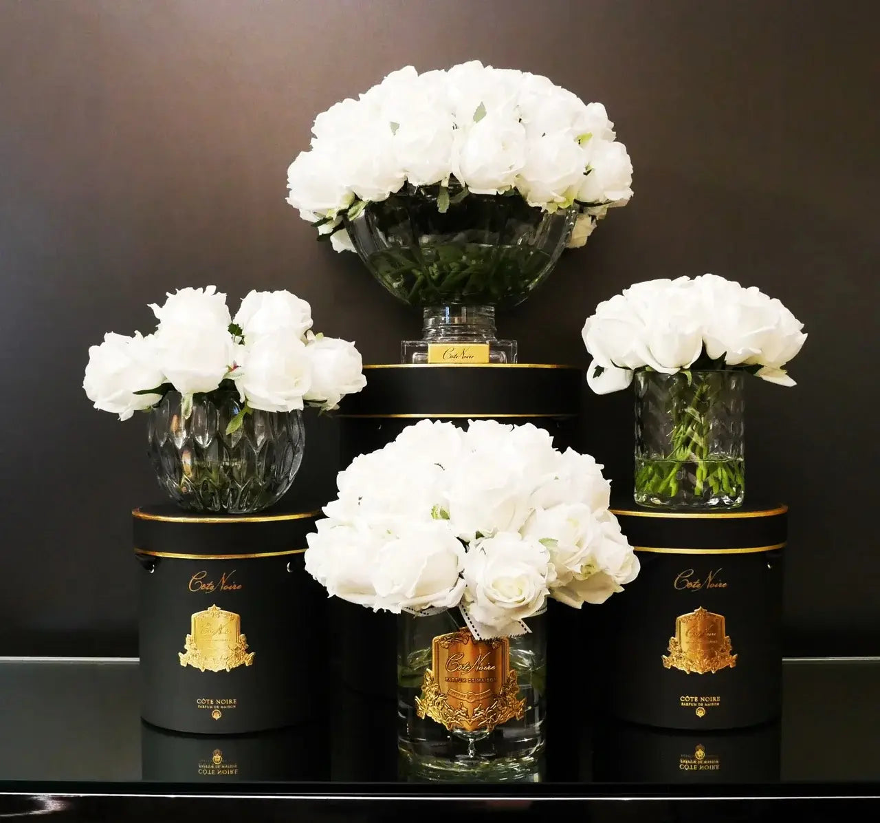 Exklusive Duftblumen in Weiß – kunstvoll arrangiert mit verschiedenen Vasen und Côte Noire Geschenkboxen in Schwarz-Gold