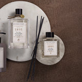 1895 duftstaebchen und eau de cologne auf kreisrunden marmorplatten.