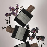 ein orchidenstaengel darauf liegend 3 glasspruhflaschen von black orchid atelier rebul