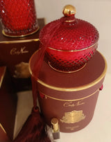 rote round art duftkerze mit quaste auf goldener zylinderfoermiger geschenkbox.