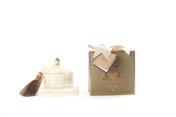 cote noire grand art duftkerze in dekorativem glas, daneben verpackung mit geschenkschleife, creme und gold.