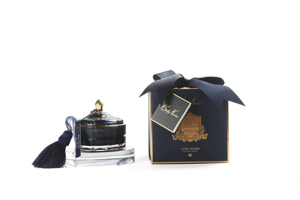 cote noire grand art duftkerze in dekorativem glas, daneben verpackung mit geschenkschleife, marineblau.