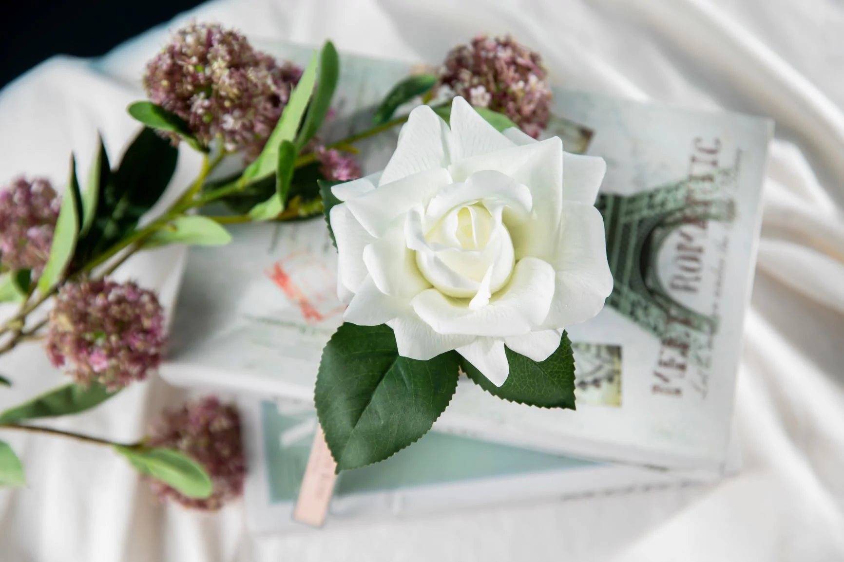 single rose auf buecherstapel aus vogelperspektive. weisse decke.