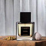 auf einem holz stehende glasspruehflasche mit schwarzem deckel steht das atelier rebul tugra Eau de Parfum