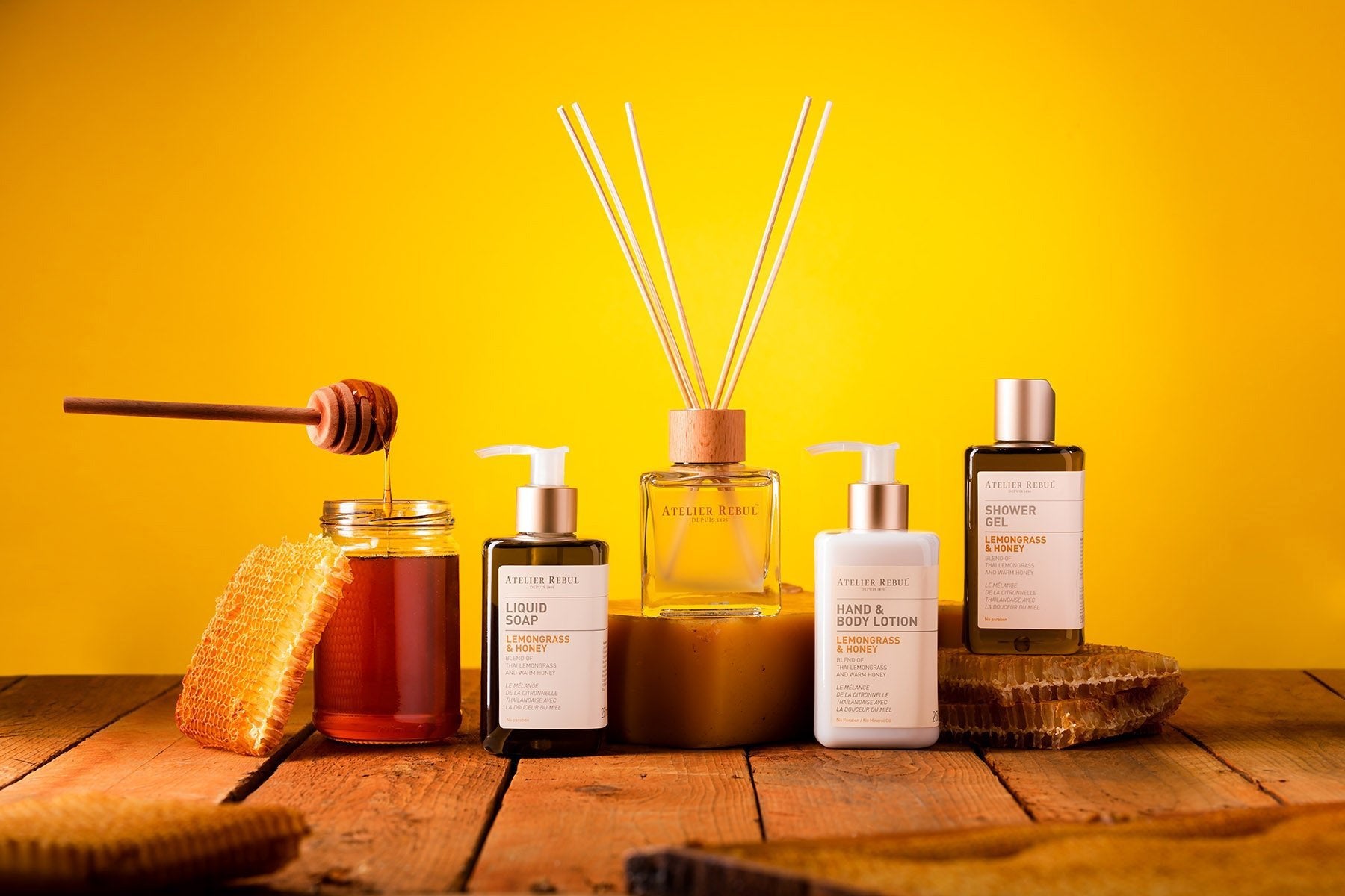 auf holz stehen produkte von atelier rebul  Lemongrass und honey sowie hoing der hintergrund ist gelb 