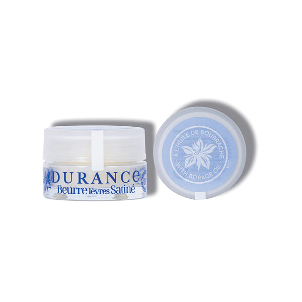 vor dem weissen hintergrund steht der dekorative cremetigel  durance lippenbutter nebendran der deckel