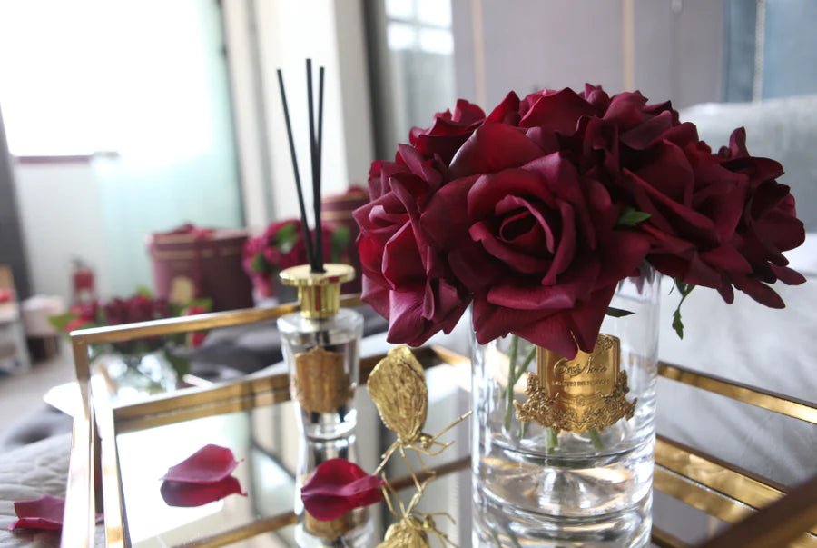 karminrote luxury grand bouquet duftblume auf einem spiegeltablett mit roten bluetenblaettern.