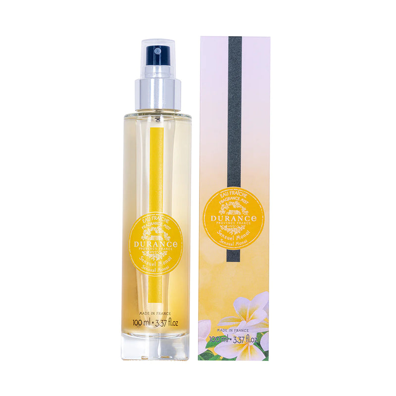 durchsichtige runde glasflasche eau fraiche sinnliches monoi mit silbernen spruehkopf und verpackung vor weissem hintergrund