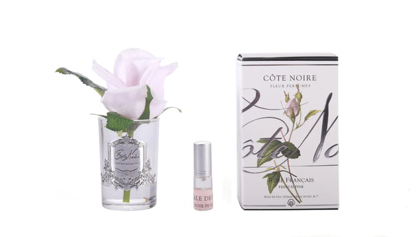 french pink single rose in hellem glas mit silbernem emblem. dazu duftspray und helle verpackung. weisser hintergrund.